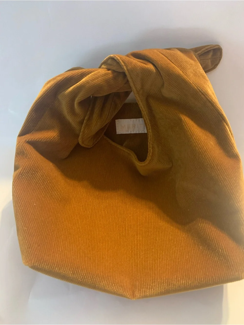 Merit Beauty Signature Bag in a golden brown or camel corduroy material